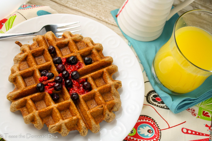 birds eye view of a wholegrain gluten free waffle on a white plate with fresh berries