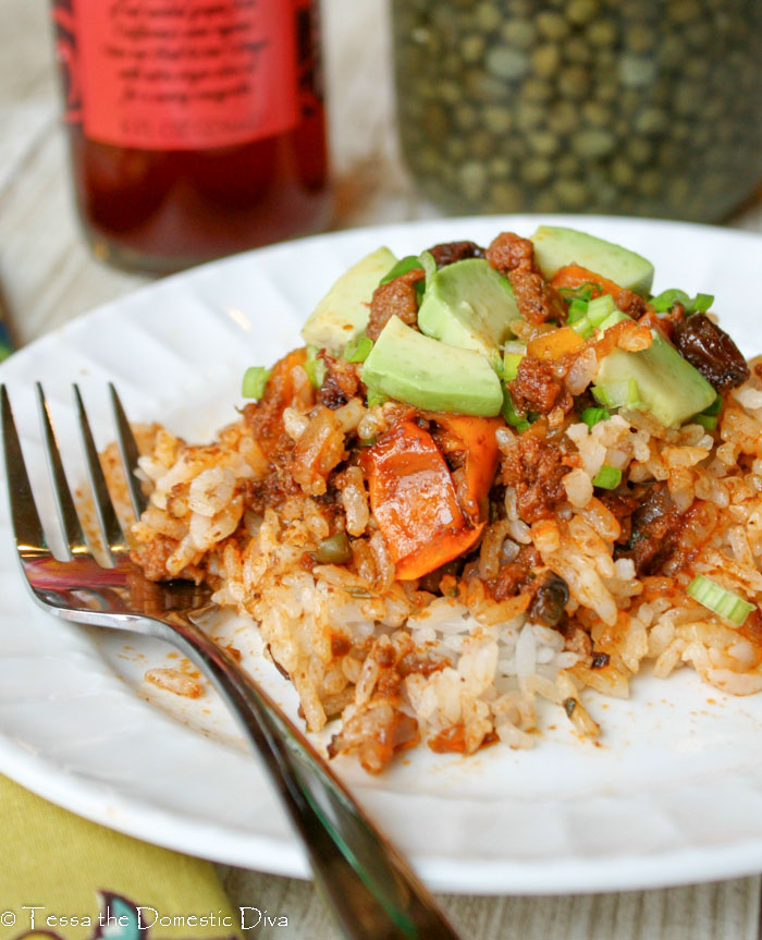 white rice on a white late mixed with ground beef, raisins, capers, in a tomato sauce with chopped fresh avocado
