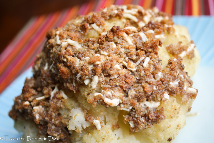 a breaded whole roasted cauliflower head on a blue plate