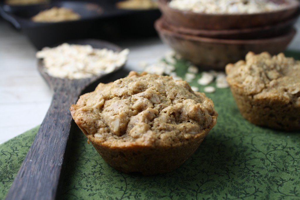 close up of a oatmeal studded muffins on a forest green cloth with a stack of wooden bowls in the background