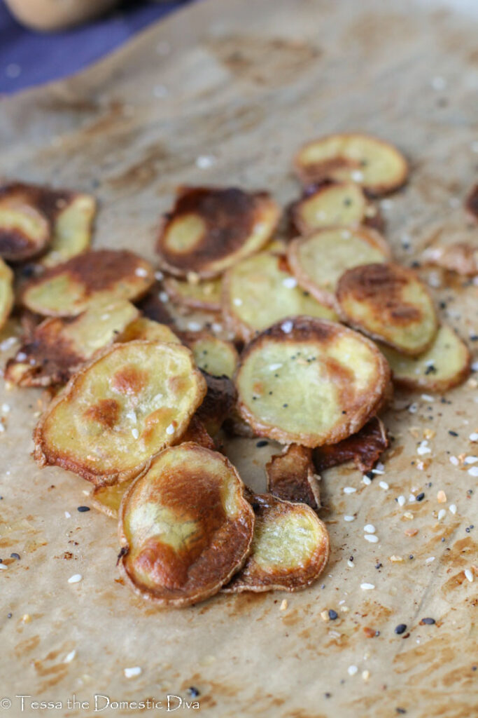 a pile of golden crispy slices of potatoes on parchment paper.