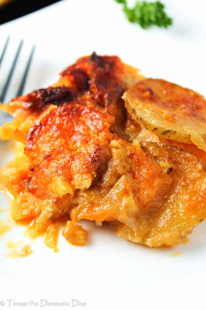 eye level scalloped potatoes on a white plate and browned top