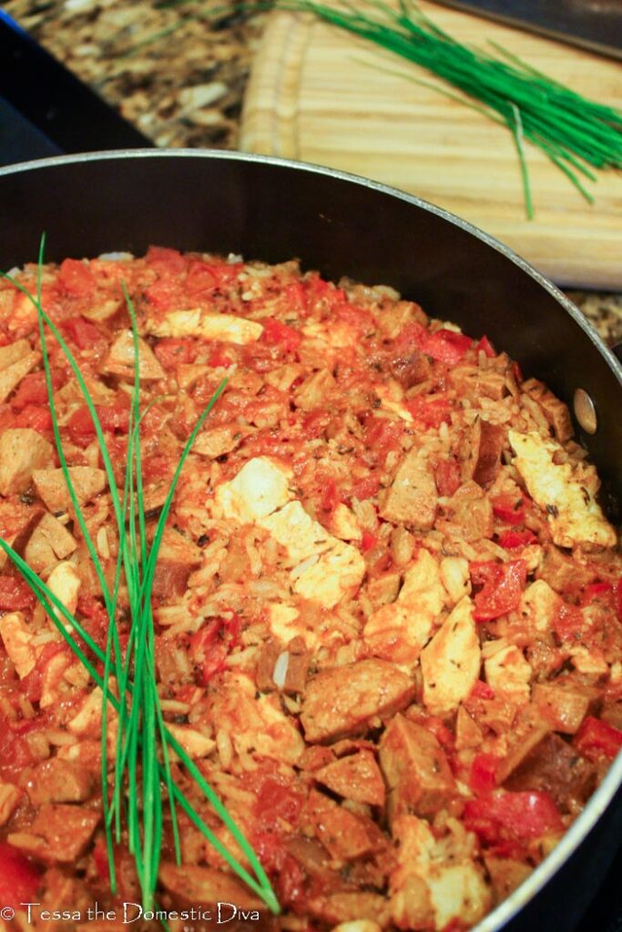 a skillet with filled with jambalaya topped with fresh chives