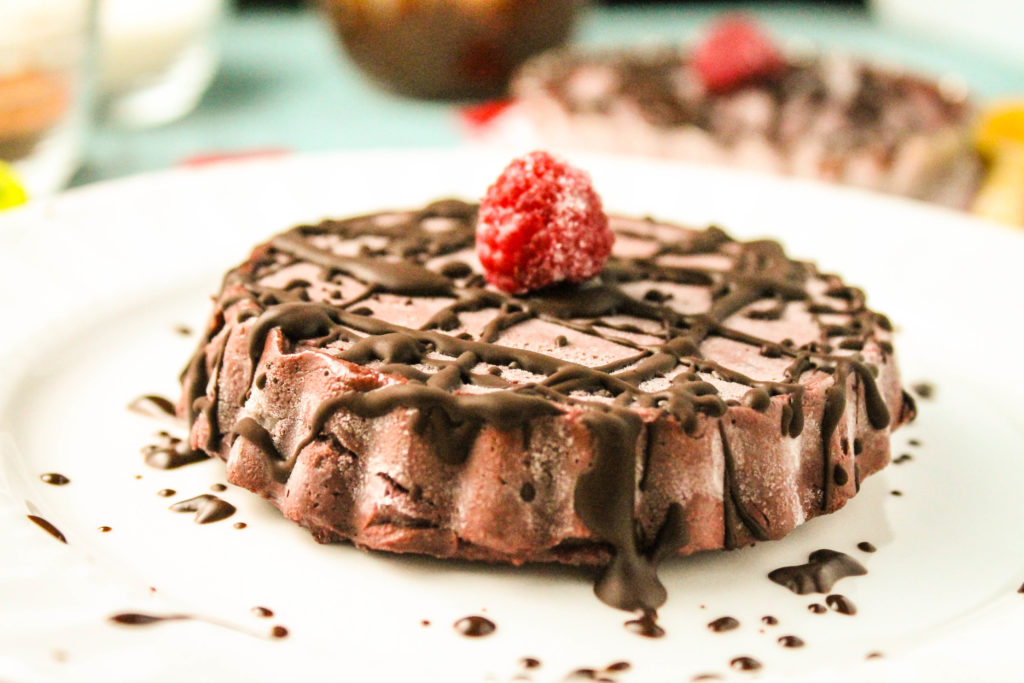 a single raw chocolate tart with raspberries and chocolate drizzle