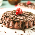 a single raw chocolate tart with raspberries and chocolate drizzle
