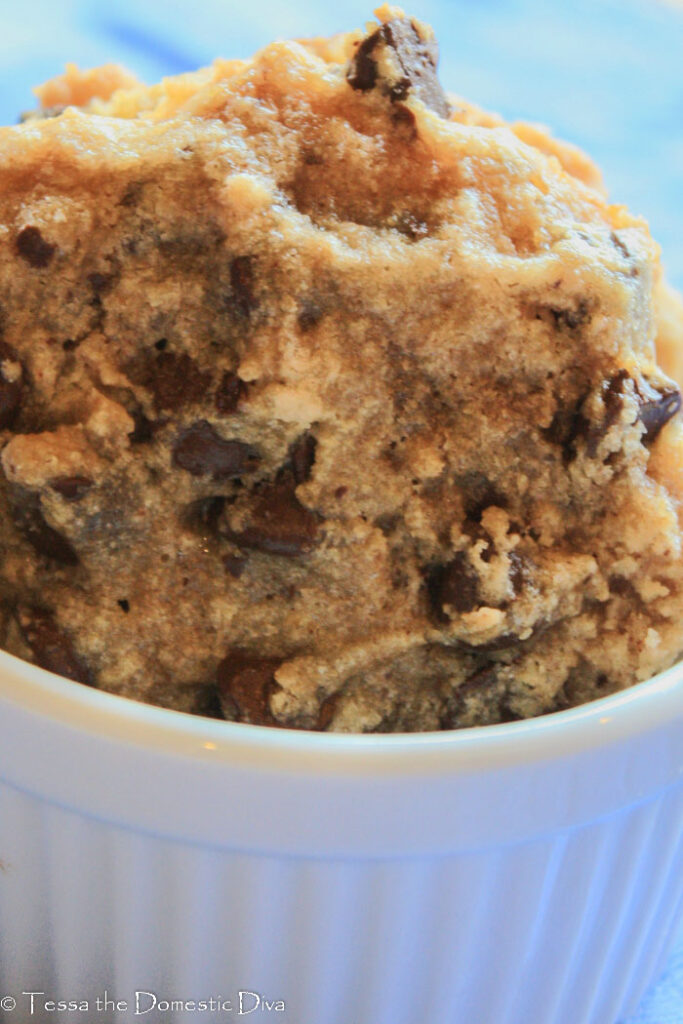 allergen free chocolate chip cookies vertically stacked in a white ramekin on a blue cloth