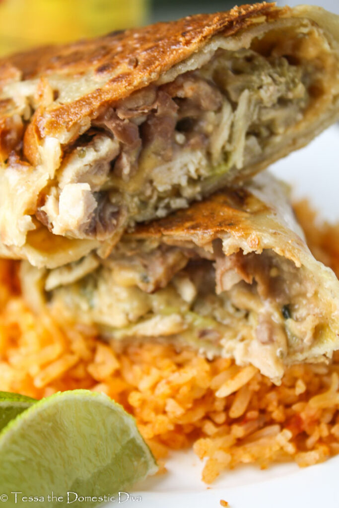 close up up of a halved baked chimichanga filled with beans, Spanish rice, and chicken