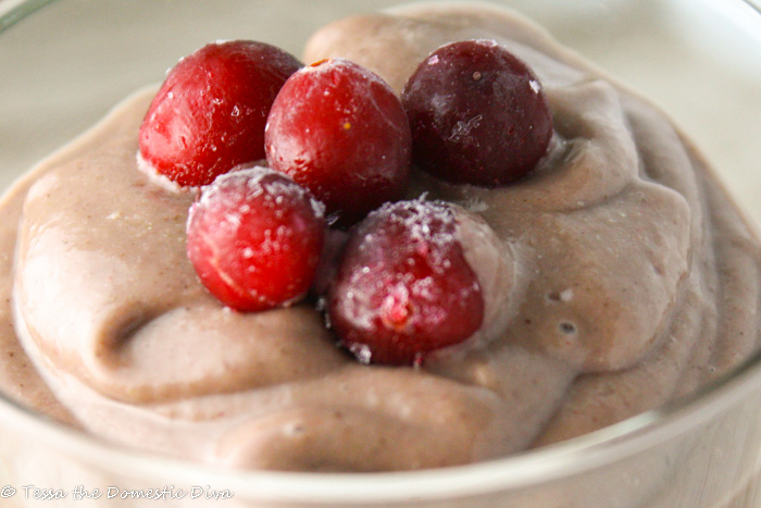 close up of bright red berries atop a creamy smoothie in a clear glass
