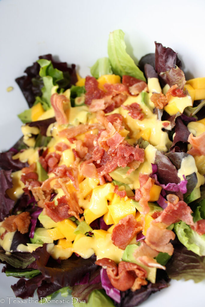 mixed green topped with a bright yello mango vinaigrette and bacon chunks