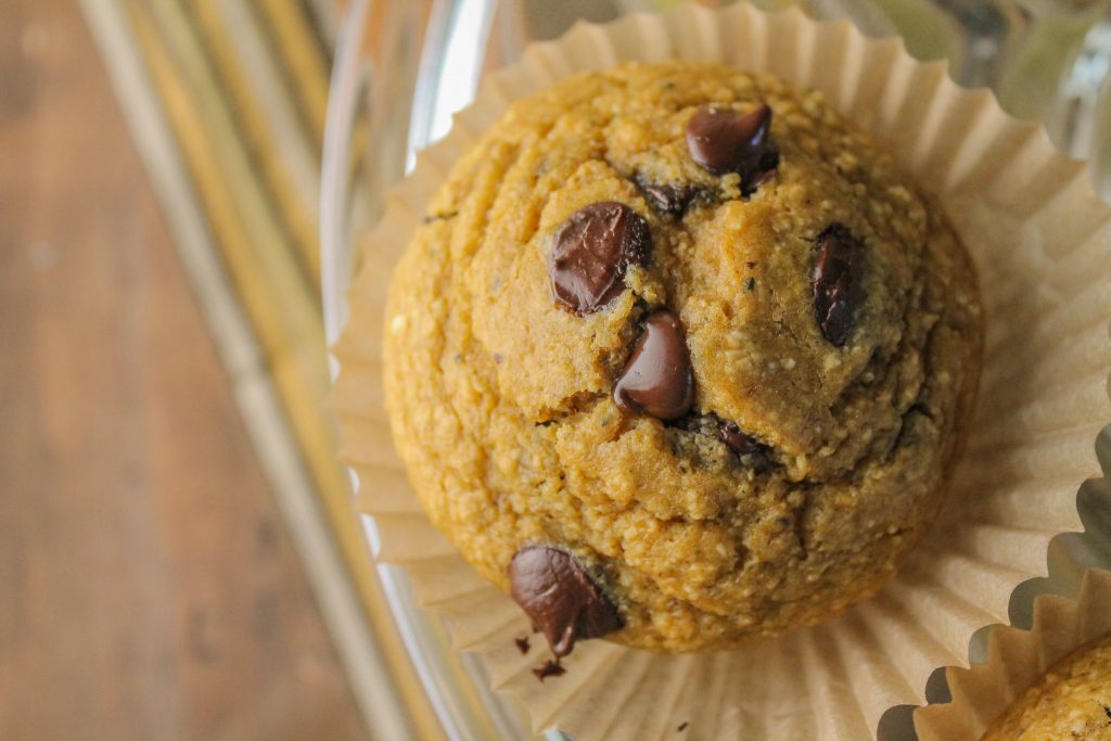 overhead close up of one hocolate studded pumpkin hemp oat muffin in a natural baking cup