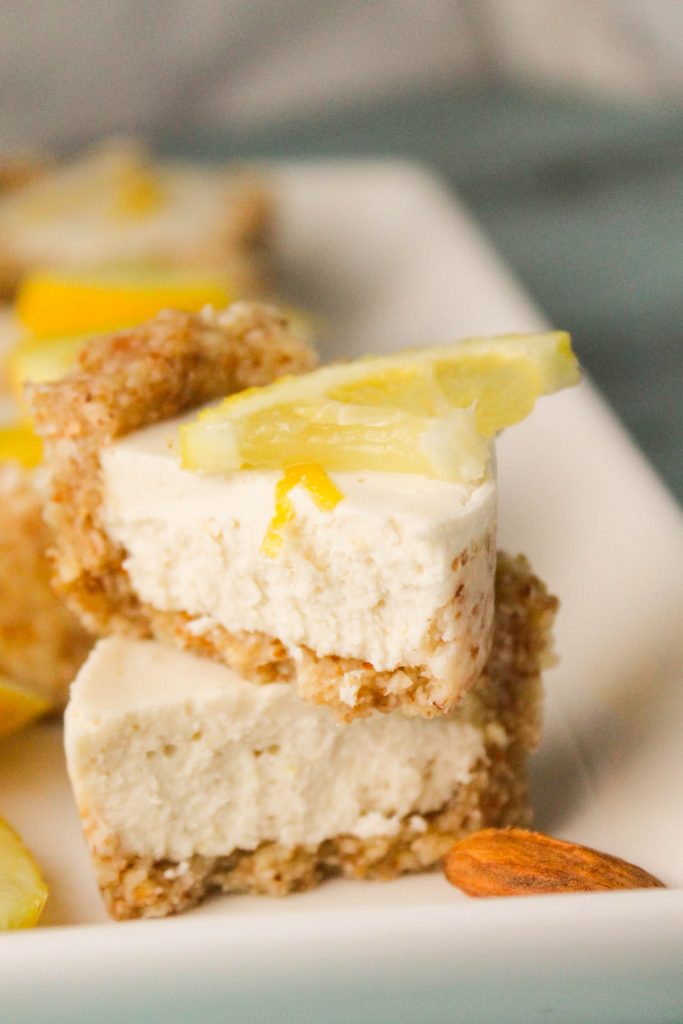 single creamy lemon cheesecake cut in half on a white plate with a lemon garnish
