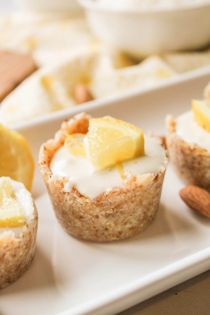 a single tart in a raw almond crust filled with a creamy lemon filling on a white plate