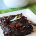 a square of moist chocolate zucchini cake topped with gooey chocolate chips and a few fresh zucchini shreds