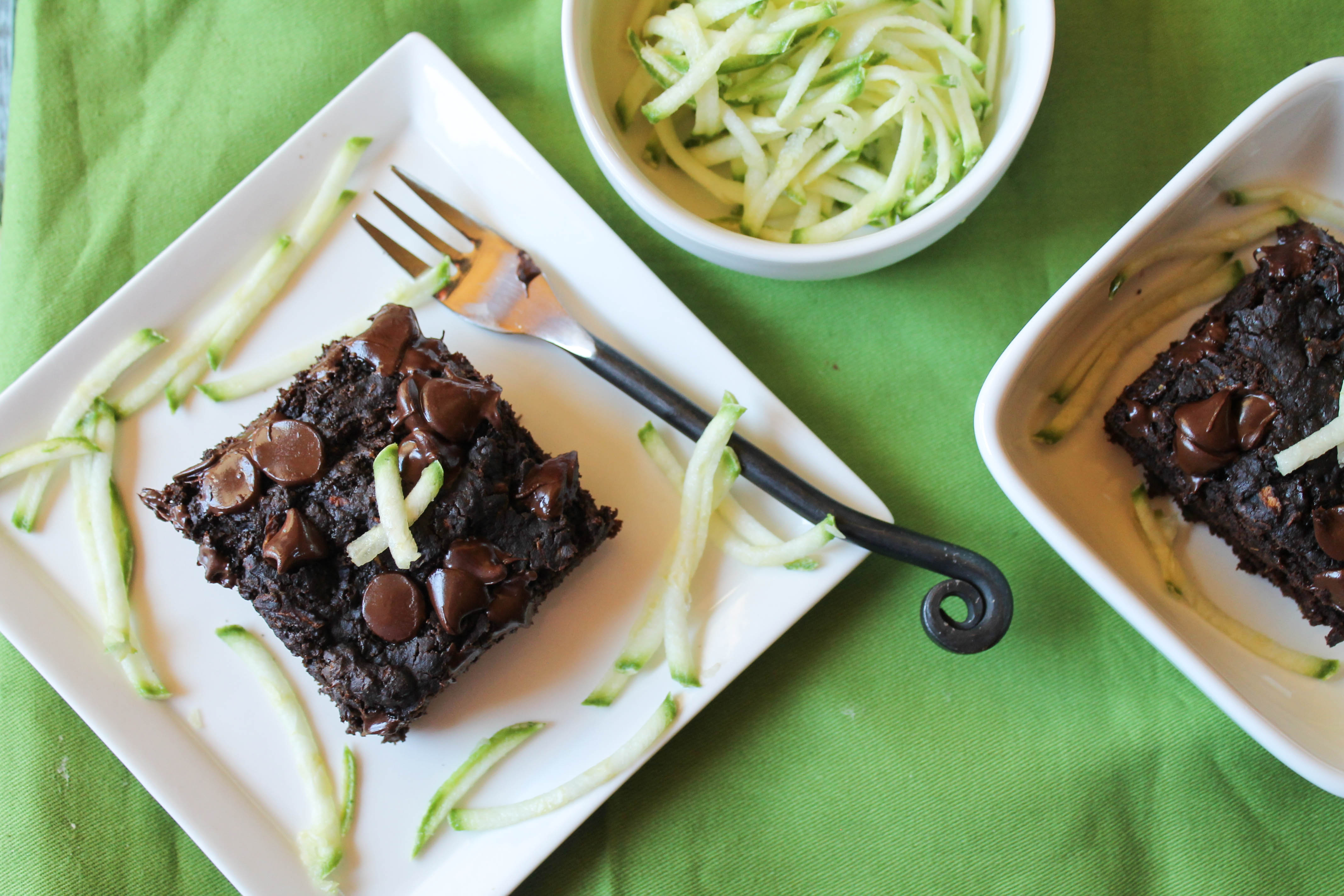 overhead shot of a square of chocolate chip studded chocolate cake with fresh zucchini shreds