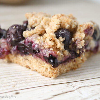 close up of a triangle slice of blueberry filled crumble bars