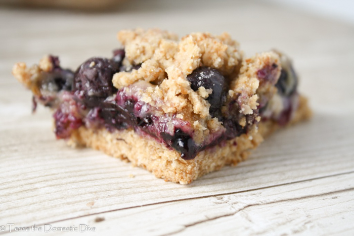 close up of a triangle slice of blueberry filled crumble bars