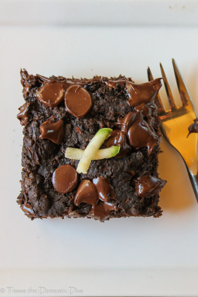 birds eye view of a chocolate chip studded chocolate cake square on a white plate.