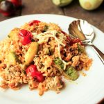 white plate filled with a hot zucchini, cheese, tomato and rice casserole on a dark wooden surface