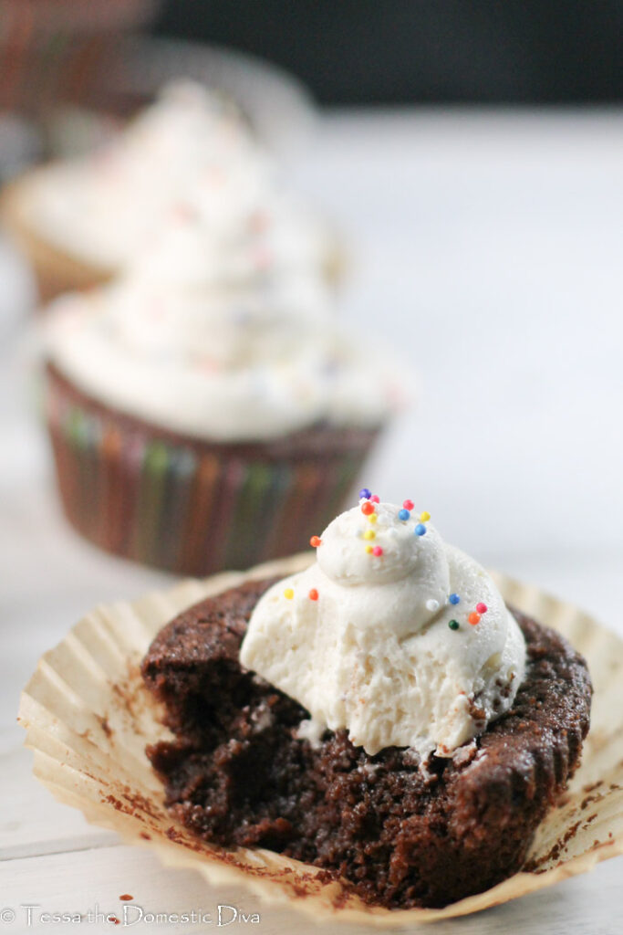 a torn chcooclate cupcake with buttercream frosting