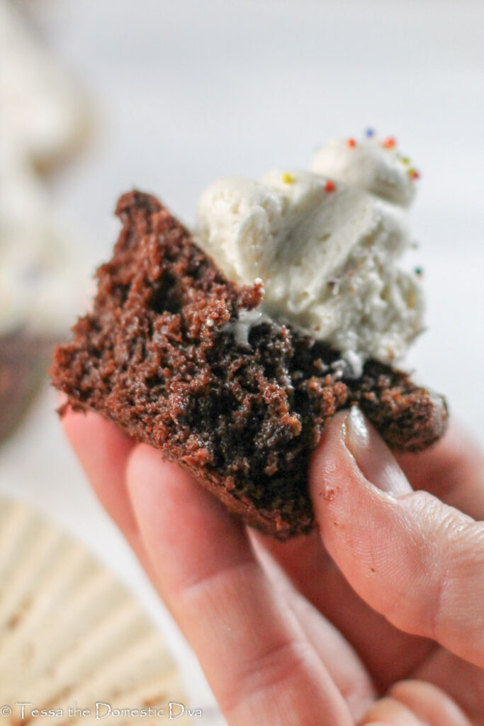 halved frosted chococlate cupcake help in hand for close up