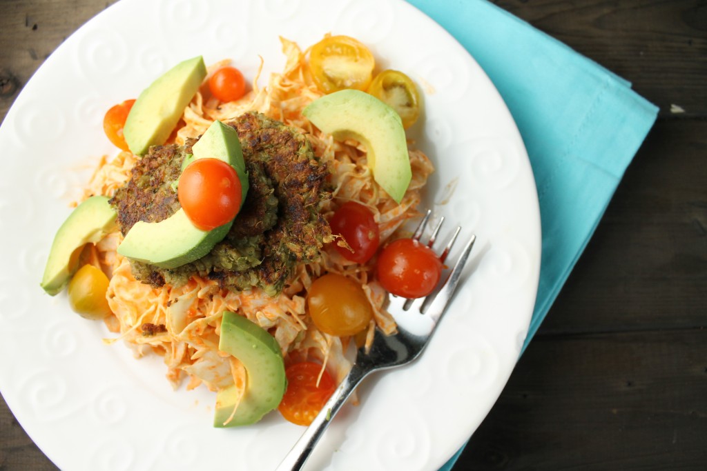 birdseye view of vegetarian mung bean falafels atop a spicy slaw with fresh tomatoes and avocado slices