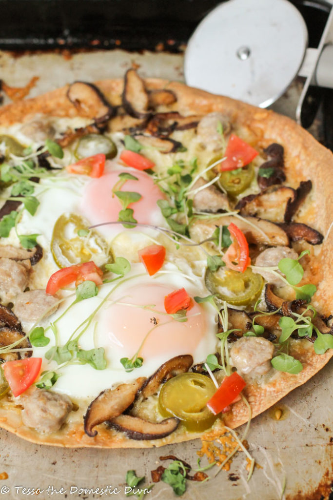 from the fron view of a crispy brown rice tortilla topped with fresh veggies, molten eggs atop a worn cookie sheet