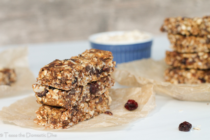 three stacked homemade granola bars on a parchment paper with cranberries.