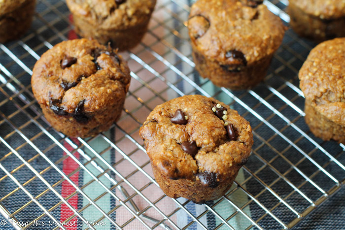 an overhead shot of chocoalt chip and whole millet studded muffins atop a cooling rack and a blue and red striped linen