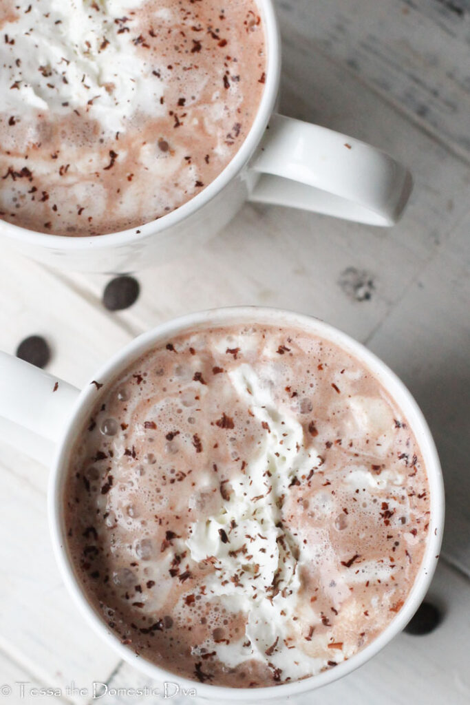 overhead view of two white mugs with healthy hot chocolate and melting whipped cream