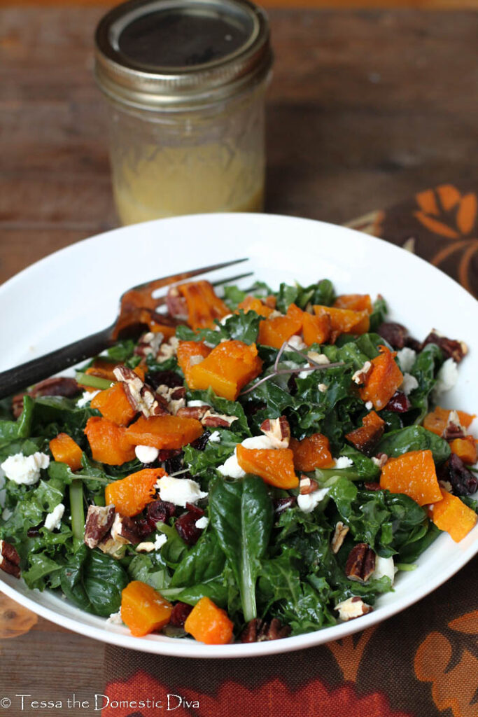 white bowl with kale salad with goat cheese, pecans, and cranberries.