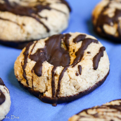 chocolate drizzled coconut shortbread cookies atop a vibrant blue fabric.