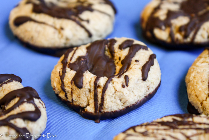 chocolate drizzled coconut shortbread cookies atop a vibrant blue fabric.