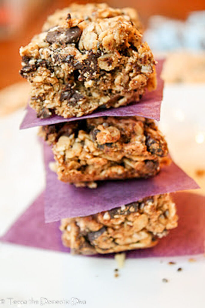 stack of three cut homemade granola bars with chococlate chips, raisins, and chia seeds