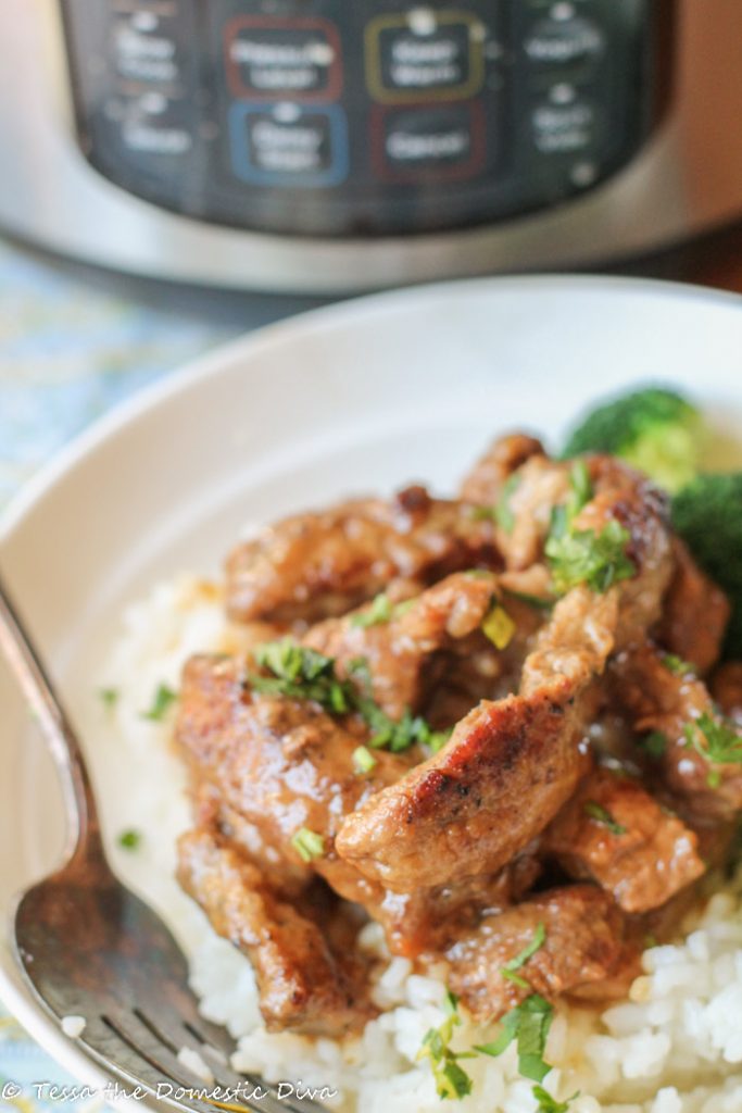 a white bowl filled with cube steak strips on a bed of sticky rice with a chopped parsely garnish and an instant pot in the background