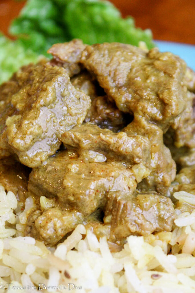 close up eye level of tender chuck roast cubes in an Indian sauce atop brown rice