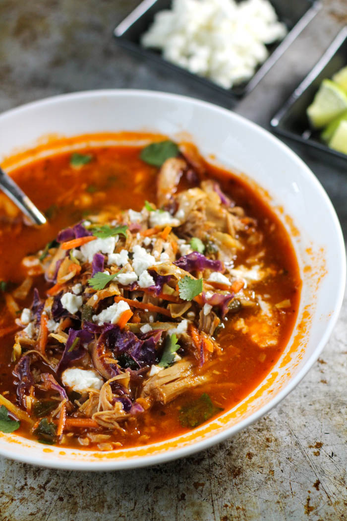 white bowl filled with a mexican flavored chicken and tomato soup with fresh cabbage and crumbled white feta cheese