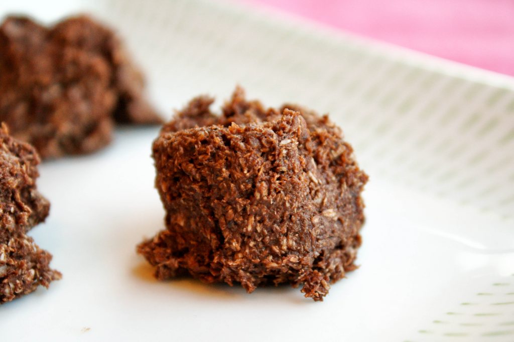 close up of a dark chocolate raw macaroon hail merry copycat on a white plate with a fuschia background