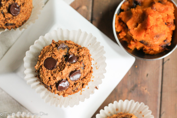 overhead view of a single chocolate chip pumpkin muffin on a white plate with fresh pumpkin