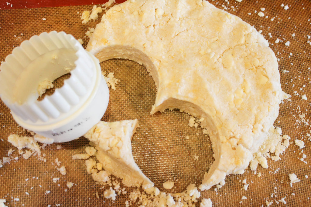 biscuit dough with cutter on a baking mat.