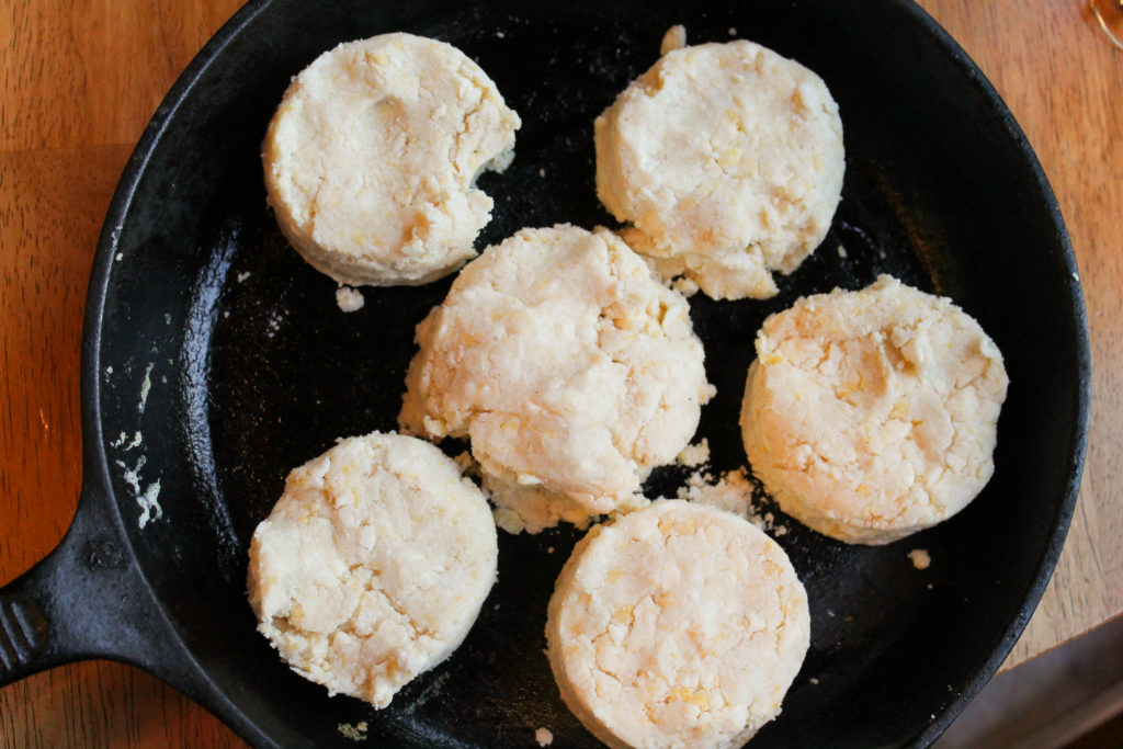 a cast iron pan with several cut biscuits ready to bake.