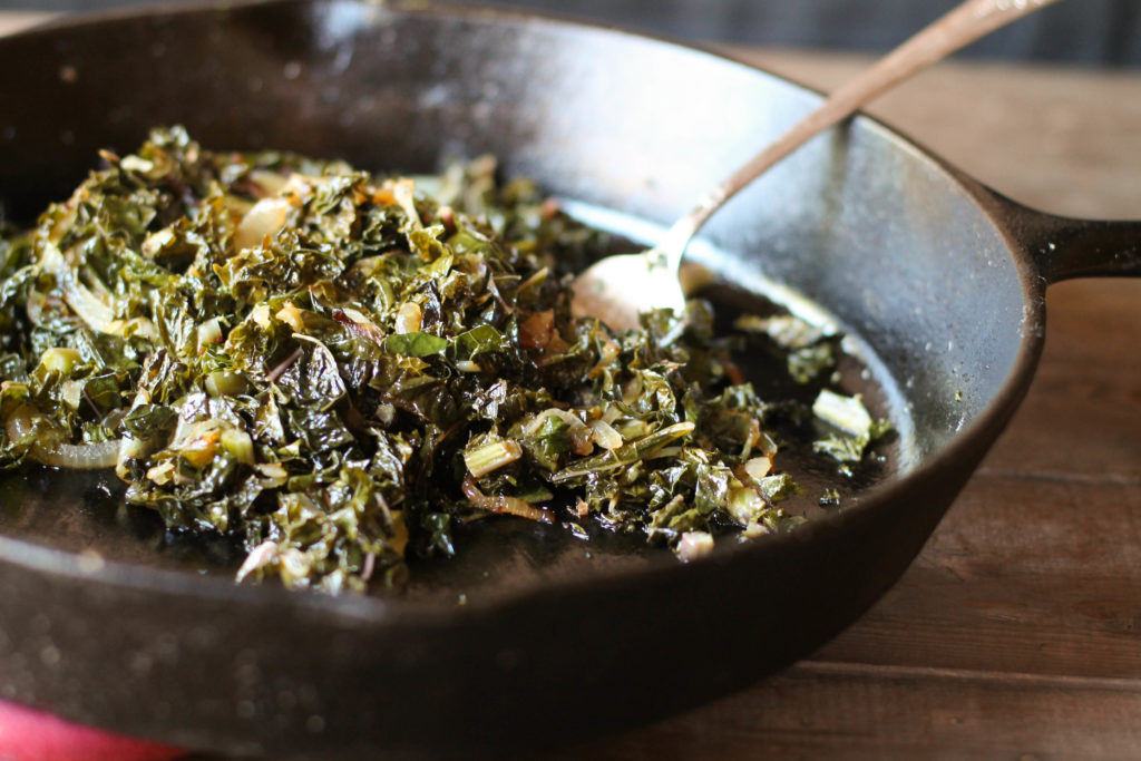 chopped lacinato kale cooked in a cast iron pan looking from the side