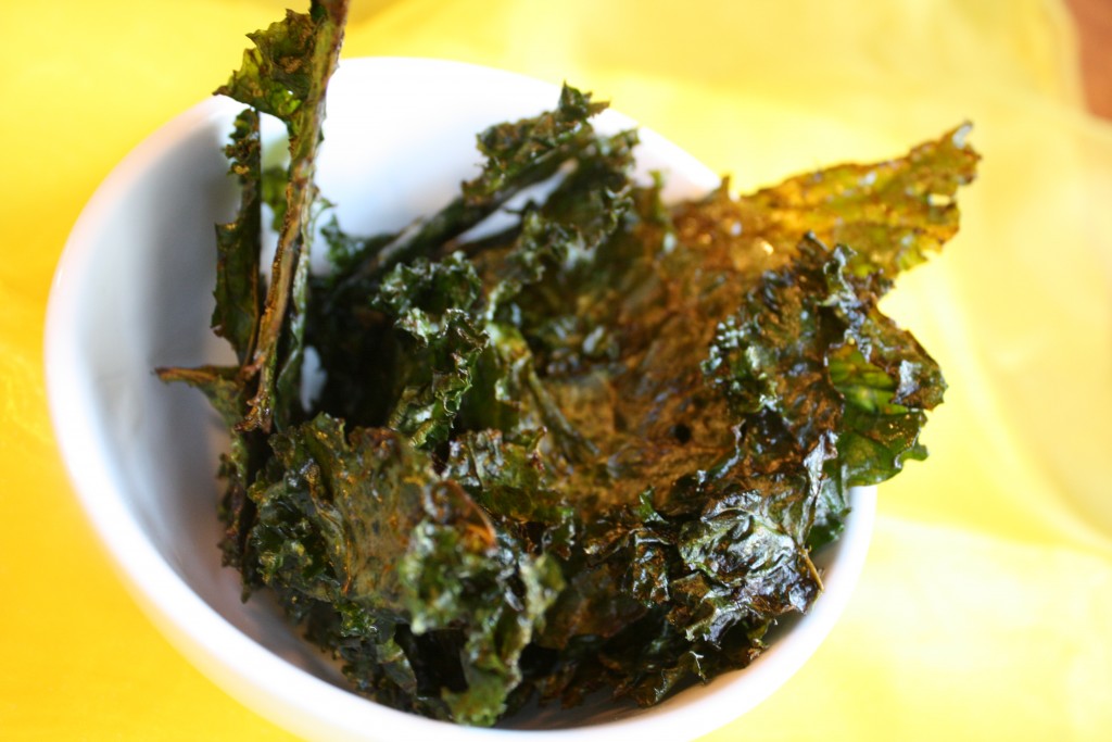 a white bowl filled with oven baked kale leaves from overhead on a bright yellow linen