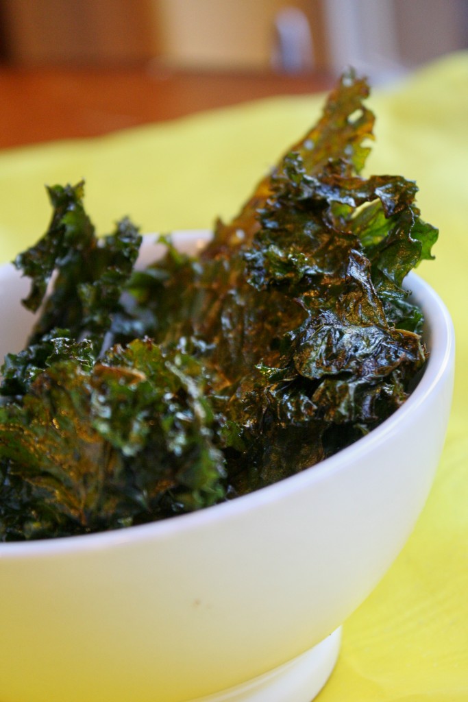 An eye level close up of a white bowl filled with crispy crunchy kale leaves