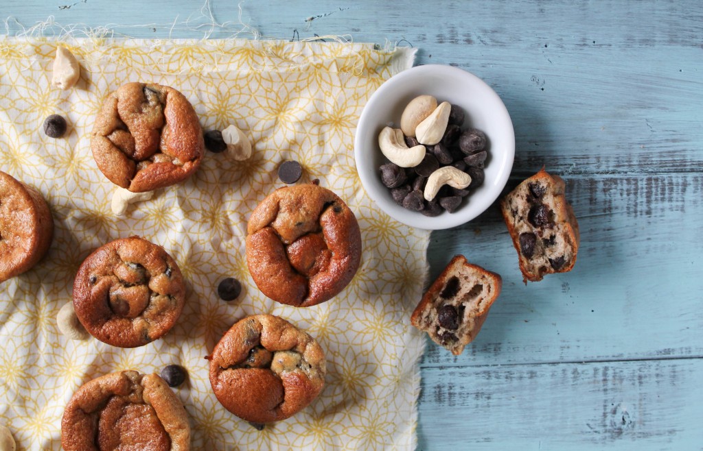 overhead shot of paleo mini banana muffins on a turquoise washed board with a bowl of chocolate chips and cashews