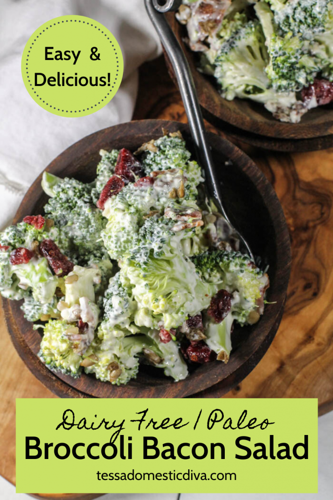 pinterest ready birds eye view of a dark wooden bowl filled with bite sized broccoli in a creamy dressing with cranberries and bacon