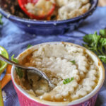 scalloped pastry circles atop a maroon ramekin of creamy cooked root vegetables and chicken thighs