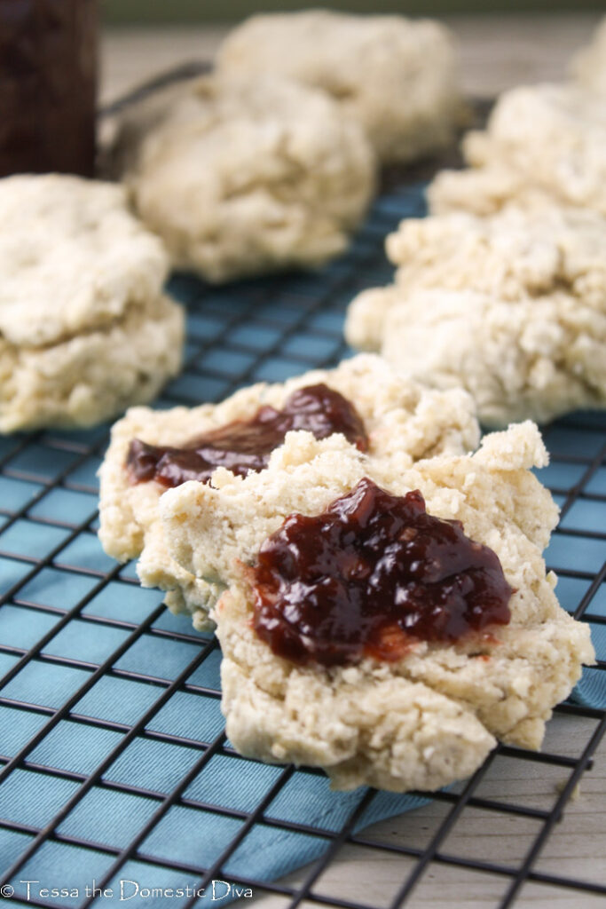 halved biscuits atop cooling racks with a topping of jelly