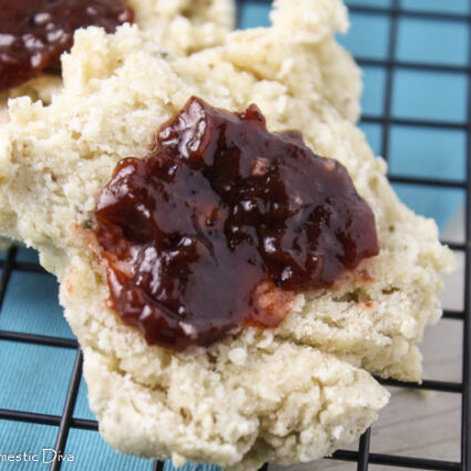 close up of a halved biscuit with berry perserves on a cooling rack with a blue napkin