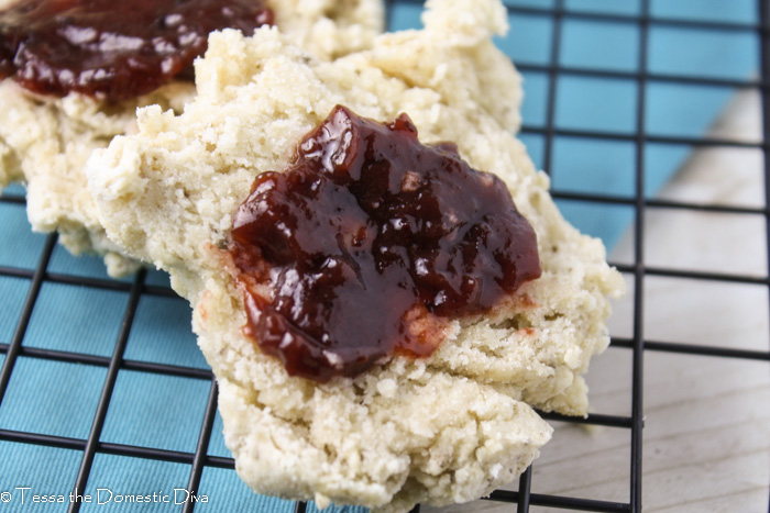 close up of a halved biscuit with berry preserves on a cooling rack with a blue napkin