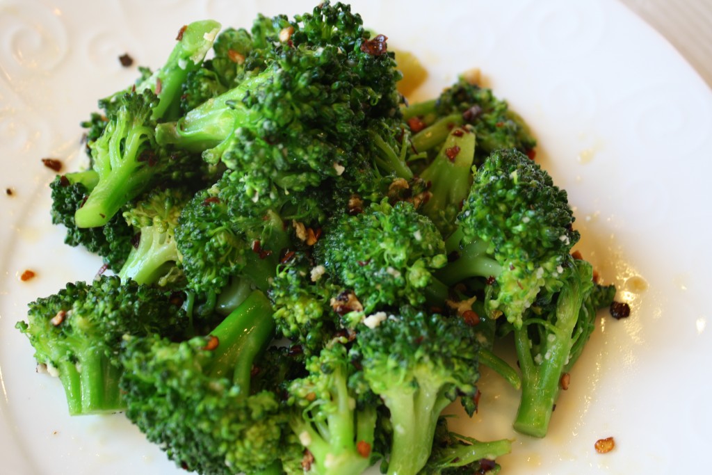overhead shot of  crisp tender stove top broccoli with garlic bits and red pepper flakes